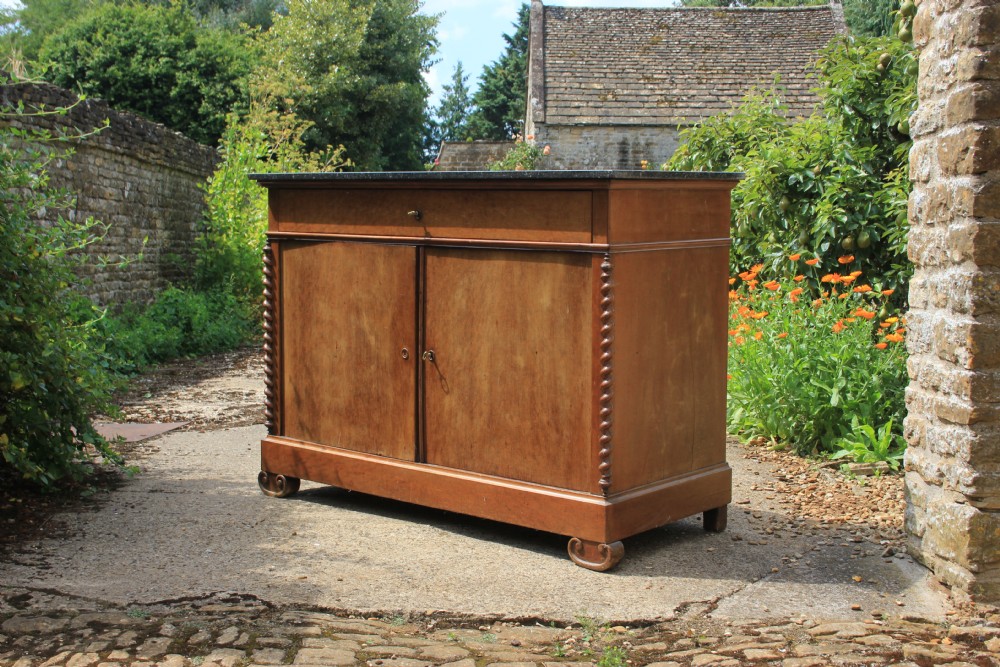 A 19th-century French walnut secretaire featuring a dark marble top, a top drawer, double cupboard doors flanked by spiral twist columns, and scroll feet.