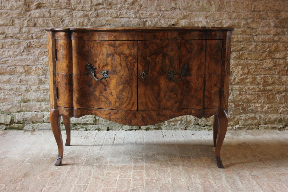 An eighteenth-century Italian walnut commode featuring a serpentine curved front, two panel doors, cabriole legs, and dark metal handles. View II