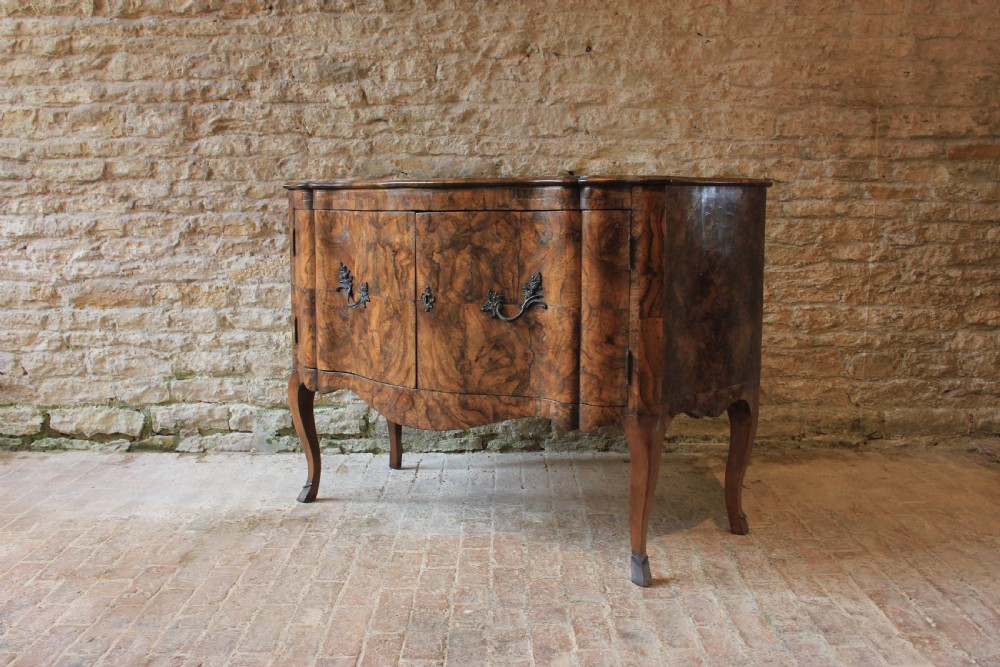 An eighteenth-century Italian walnut commode featuring a serpentine curved front, two panel doors, cabriole legs, and dark metal handles. View V