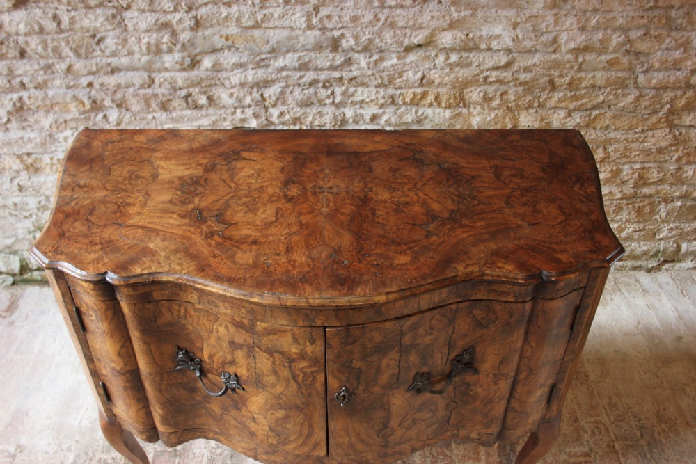An eighteenth-century Italian walnut commode featuring a serpentine curved front, two panel doors, cabriole legs, and dark metal handles. View VII