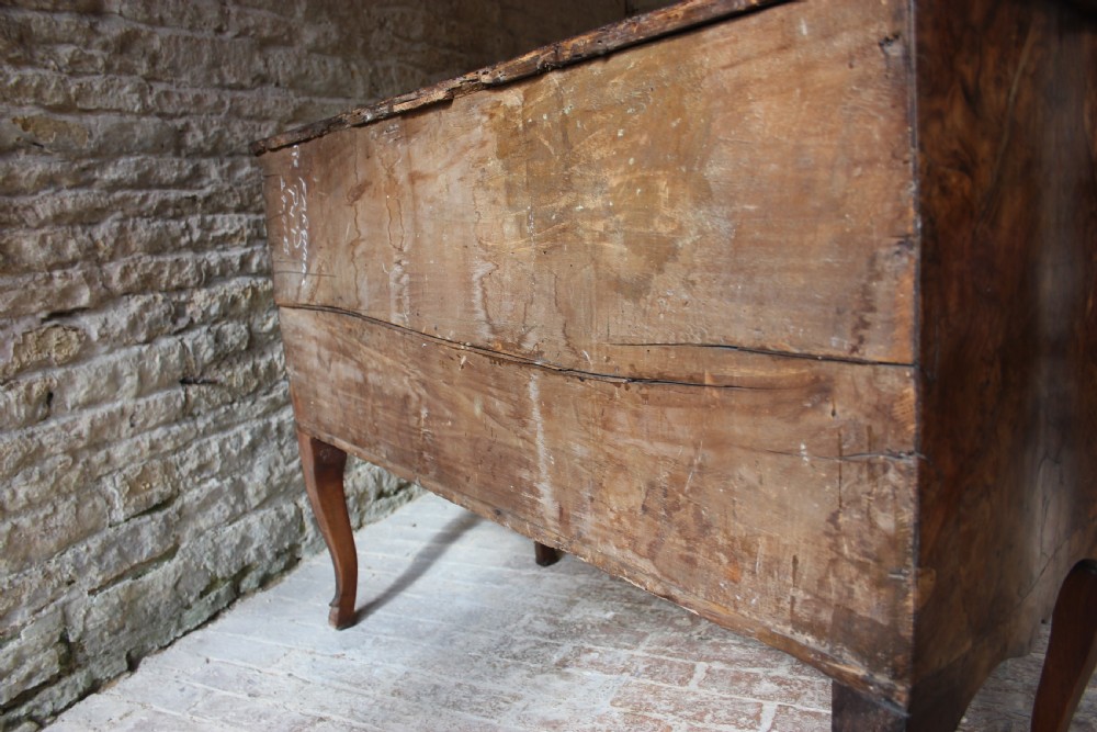 An eighteenth-century Italian walnut commode featuring a serpentine curved front, two panel doors, cabriole legs, and dark metal handles. View IX