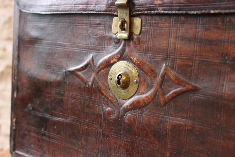 A 19th-century patinated brown leather attache case featuring a top handle, fold-over flap, brass clasp, and decorative embossed detailing around a central brass keyhole. View II