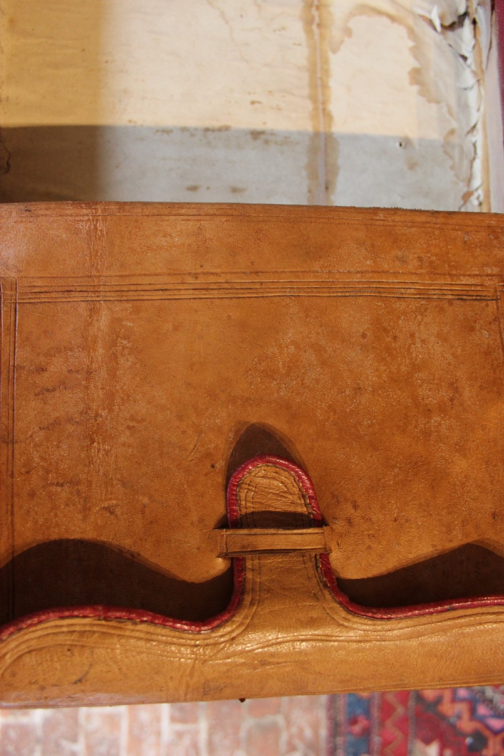 A 19th-century patinated brown leather attache case featuring a top handle, fold-over flap, brass clasp, and decorative embossed detailing around a central brass keyhole. View VII