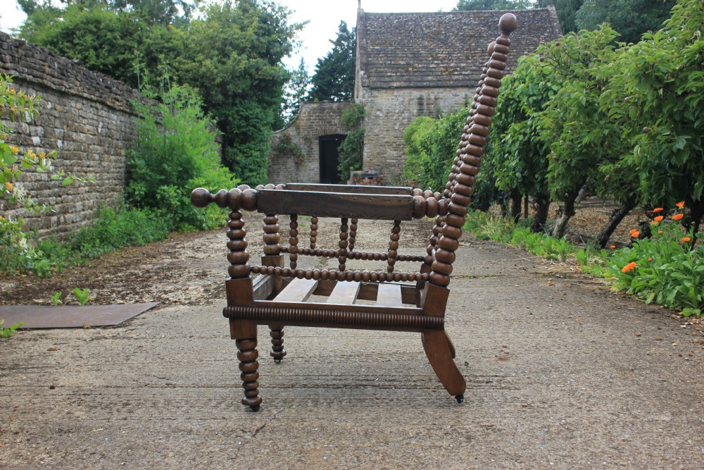 A 19th-century walnut armchair frame featuring lathe-turned bobbin spindles on the backrest, legs, and arm supports on small brass castors. View III