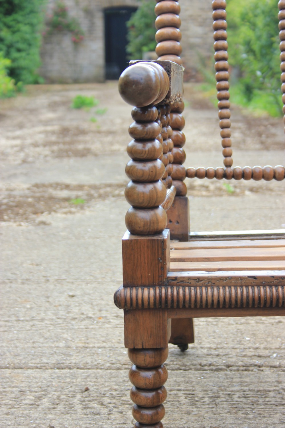 A 19th-century walnut armchair frame featuring lathe-turned bobbin spindles on the backrest, legs, and arm supports on small brass castors. View IV
