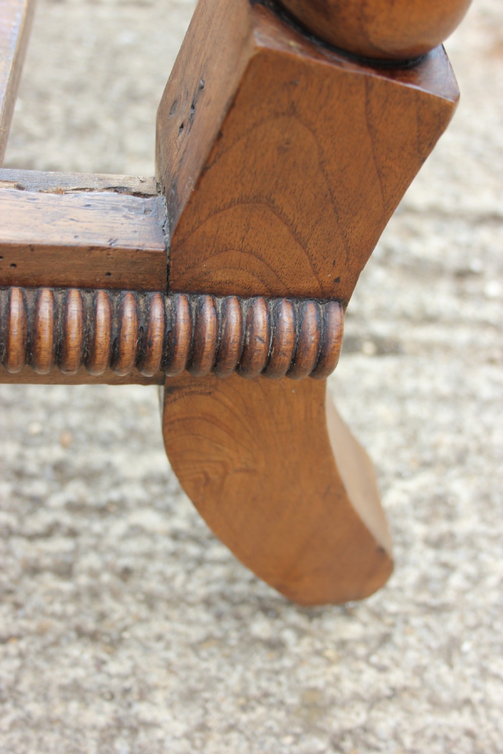 A 19th-century walnut armchair frame featuring lathe-turned bobbin spindles on the backrest, legs, and arm supports on small brass castors. View V