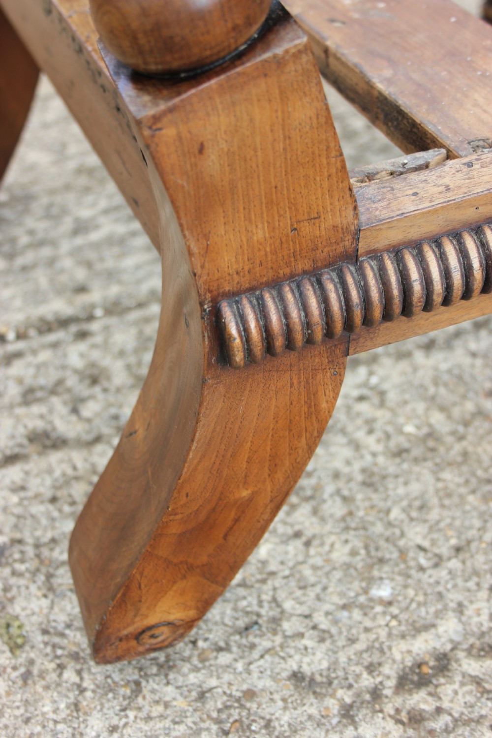 A 19th-century walnut armchair frame featuring lathe-turned bobbin spindles on the backrest, legs, and arm supports on small brass castors. View VI
