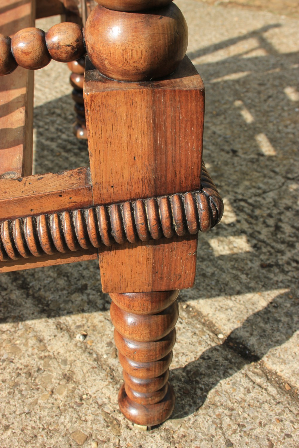 A 19th-century walnut armchair frame featuring lathe-turned bobbin spindles on the backrest, legs, and arm supports on small brass castors. View VIII