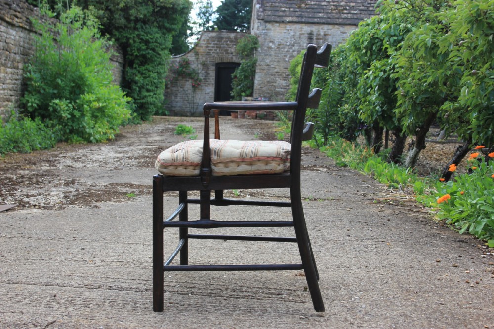 An 18th-century dark ash Sussex armchair featuring turned uprights, a ladderback frame, shaped armrests, and a striped fabric seat cushion. View II