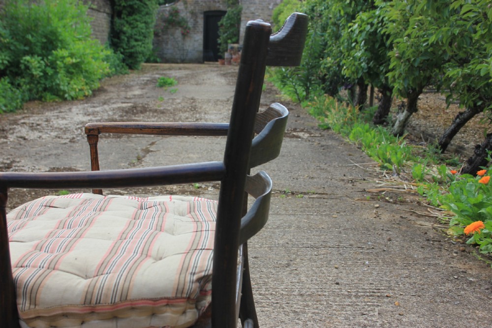 An 18th-century dark ash Sussex armchair featuring turned uprights, a ladderback frame, shaped armrests, and a striped fabric seat cushion. View III