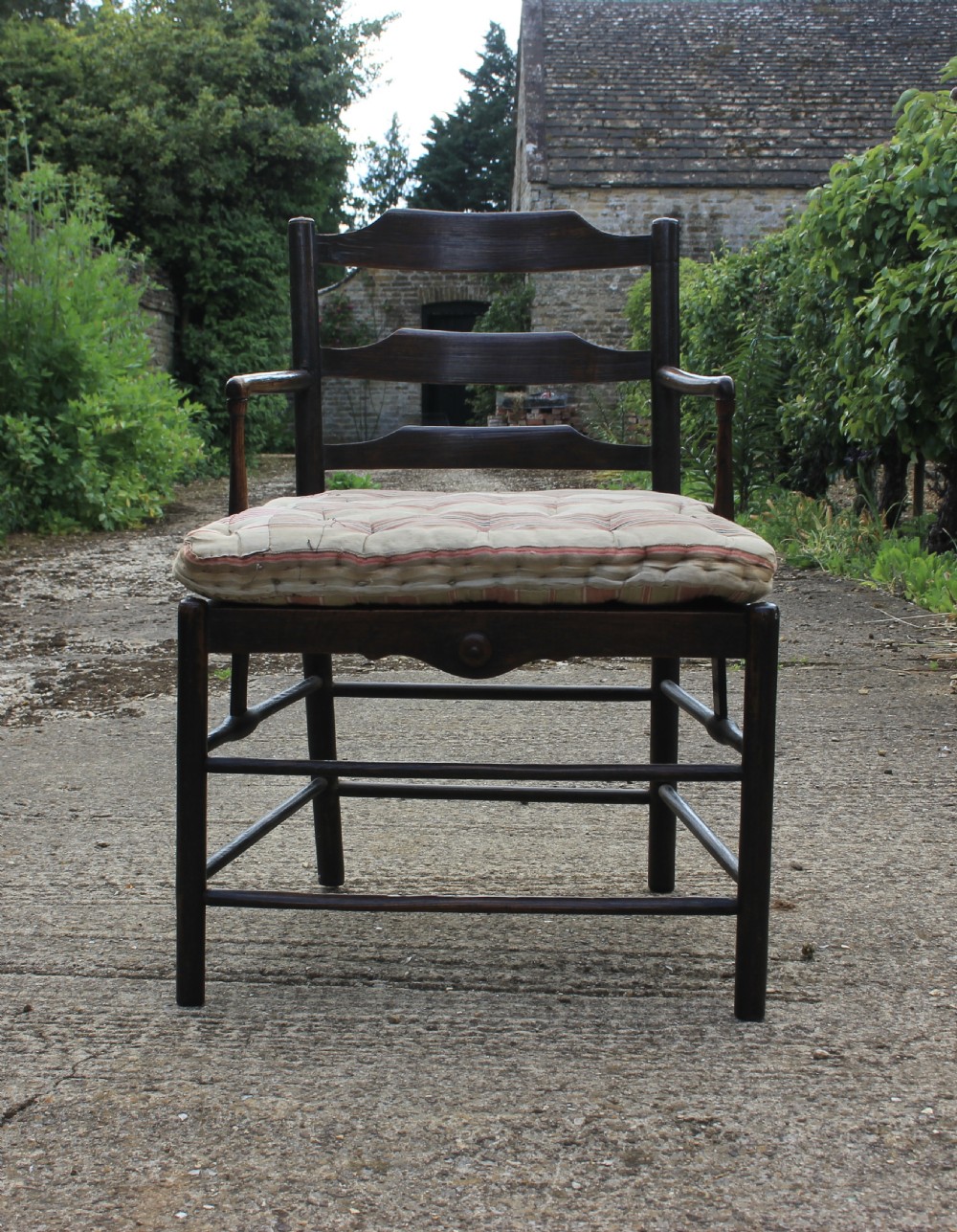 An 18th-century dark ash Sussex armchair featuring turned uprights, a ladderback frame, shaped armrests, and a striped fabric seat cushion. View IV
