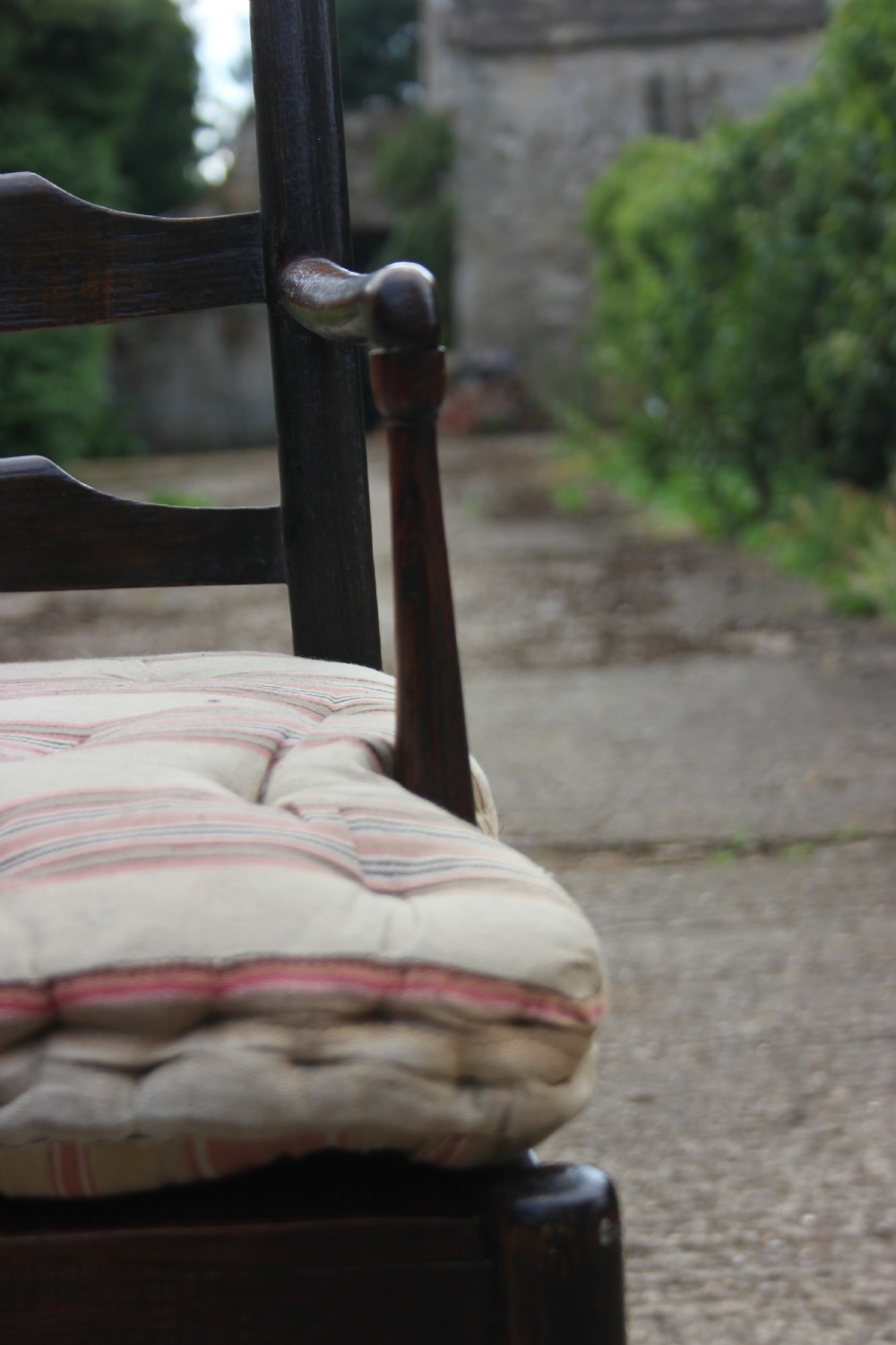 An 18th-century dark ash Sussex armchair featuring turned uprights, a ladderback frame, shaped armrests, and a striped fabric seat cushion. View VI