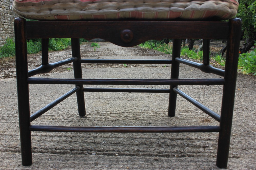 An 18th-century dark ash Sussex armchair featuring turned uprights, a ladderback frame, shaped armrests, and a striped fabric seat cushion. View VII
