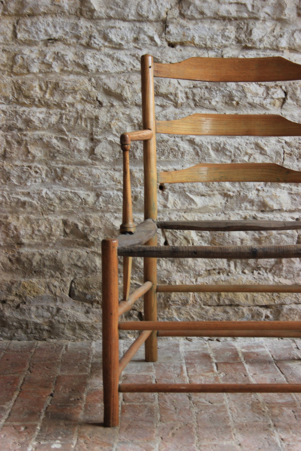 A low-slung Scandinavian light wood nursing chair featuring horizontal ladderback splats, turned arm supports, and multiple stretchers. View III