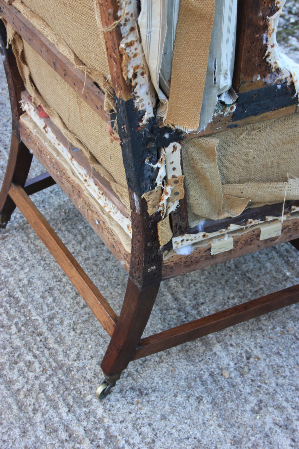 An early 18th-century wingback armchair featuring a dark timber frame, prominent side wings, and worn beige calico upholstery. View XII