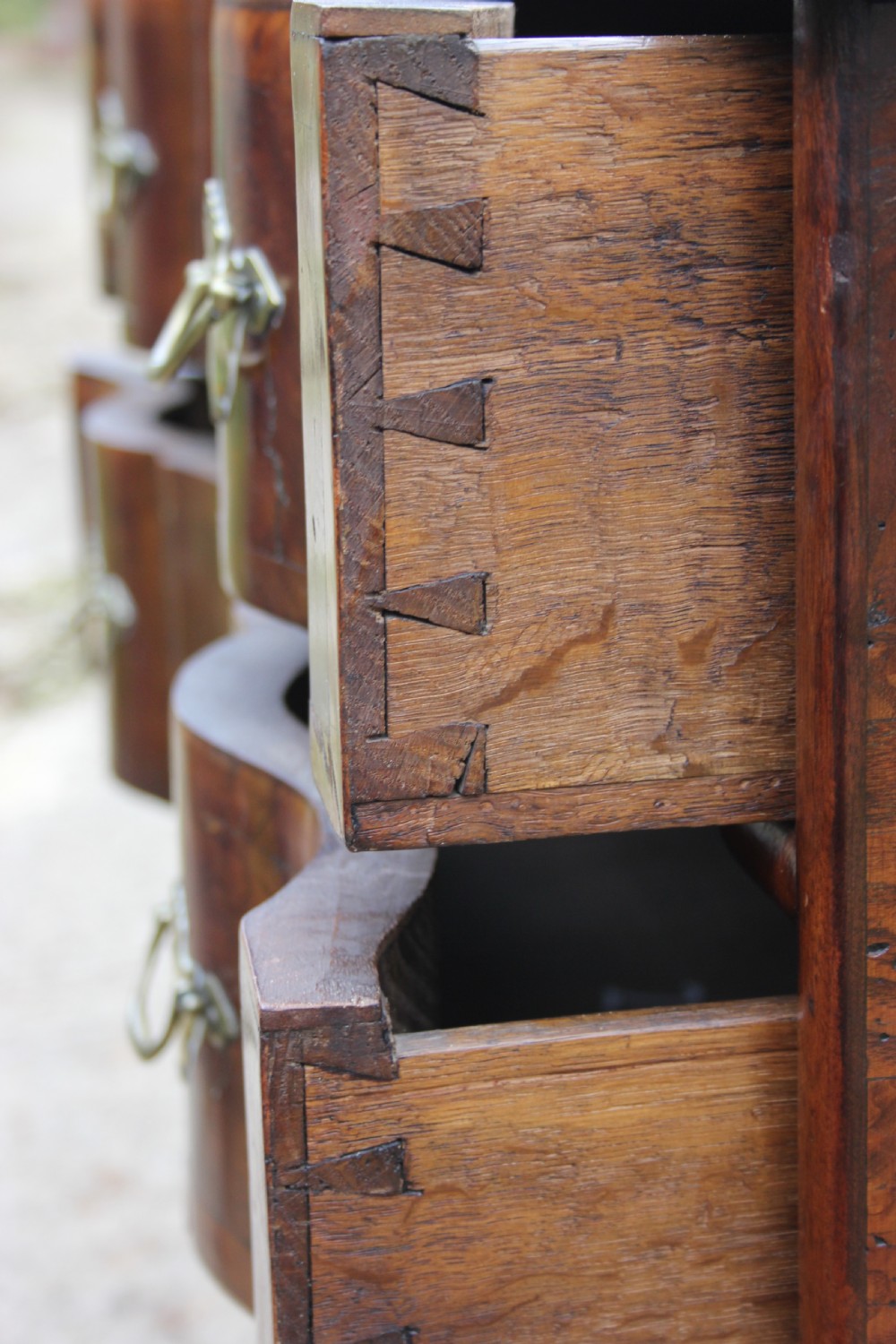An 18th-century Dutch elm chest of drawers featuring four shaped serpentine drawers with brass drop handles and side carrying handles. View X