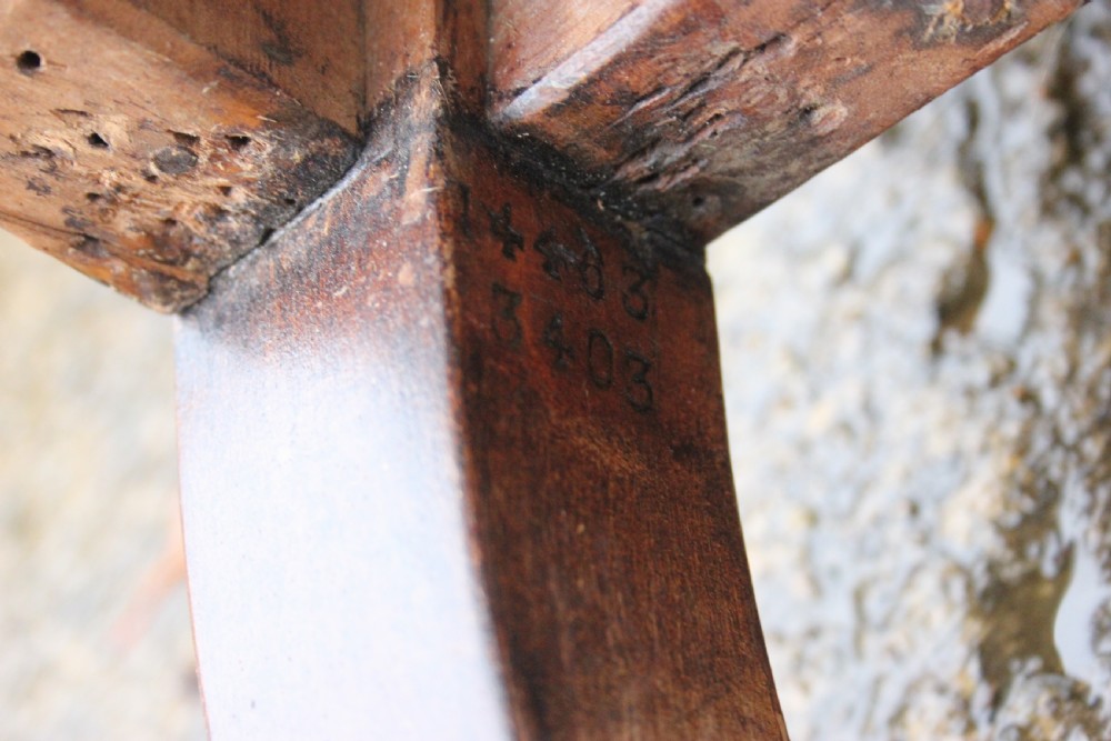 An antique Victorian Howard and Sons armchair frame featuring exposed horsehair padding, turned front legs with brass castors, and splayed back legs. View V