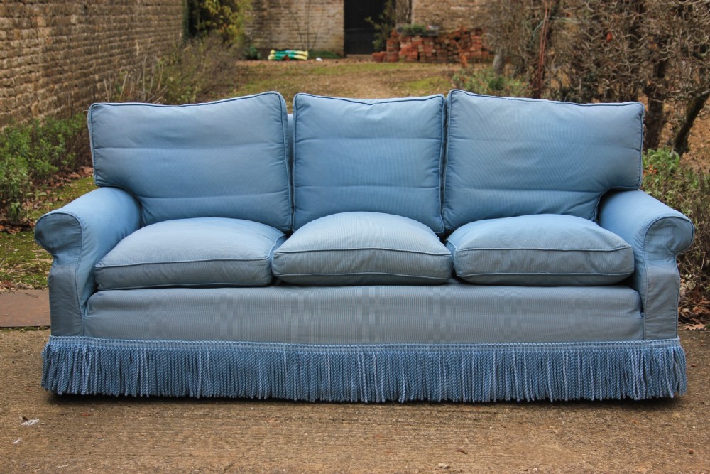 A three-seater English country house sofa upholstered in light blue fabric featuring a deep bullion fringe skirt. View IV