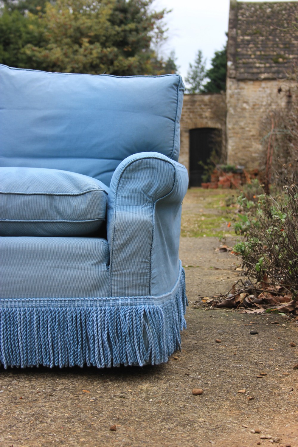 A three-seater English country house sofa upholstered in light blue fabric featuring a deep bullion fringe skirt. View V