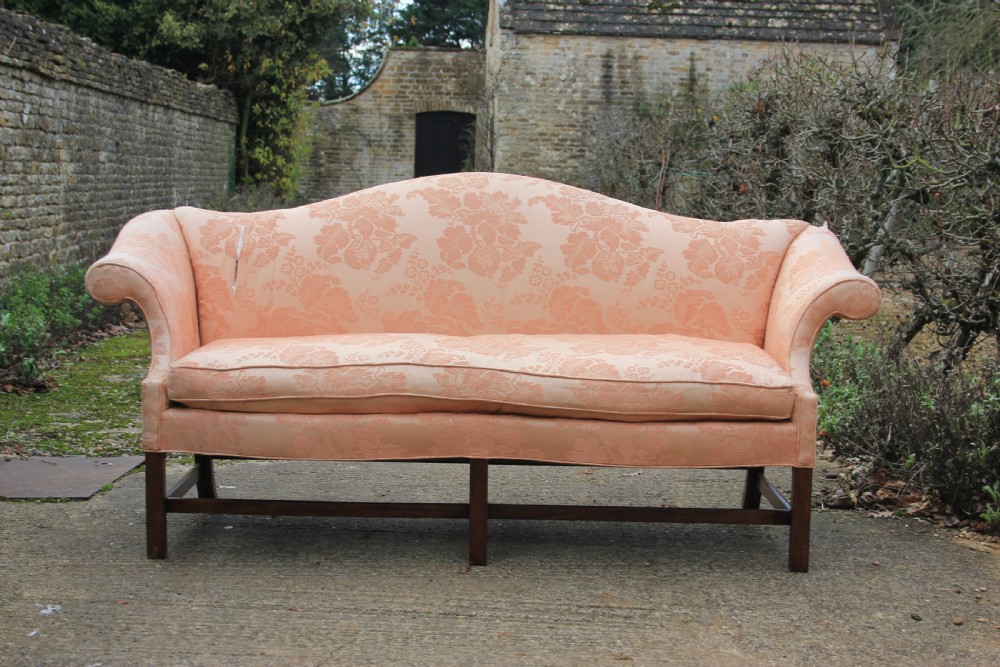 A peach damask upholstered camel back sofa featuring a serpentine seat cushion, out-scrolled arms, and square mahogany legs connected by stretchers. View II