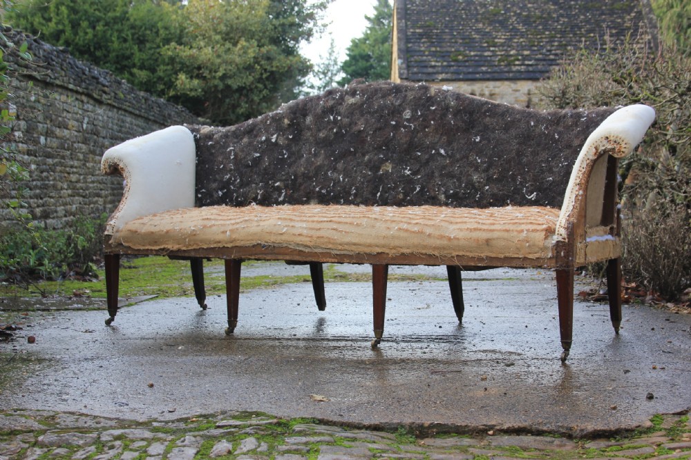 An 18th-century camel back sofa featuring a serpentine front rail, scrolled arms, and tapered mahogany legs. View II