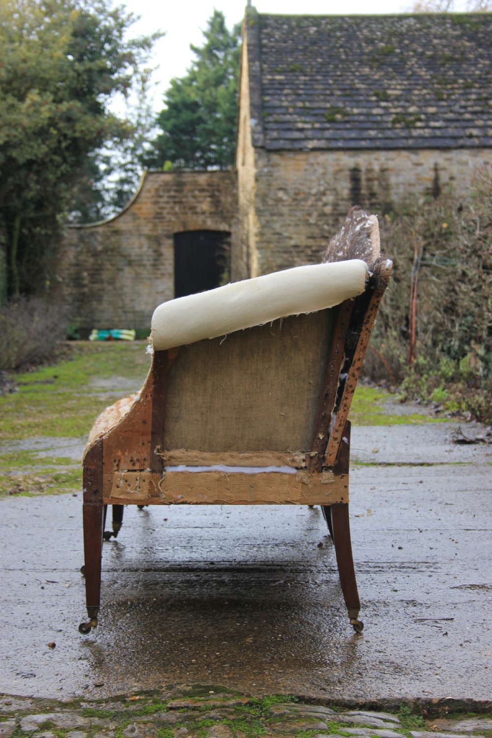 An 18th-century camel back sofa featuring a serpentine front rail, scrolled arms, and tapered mahogany legs. View III