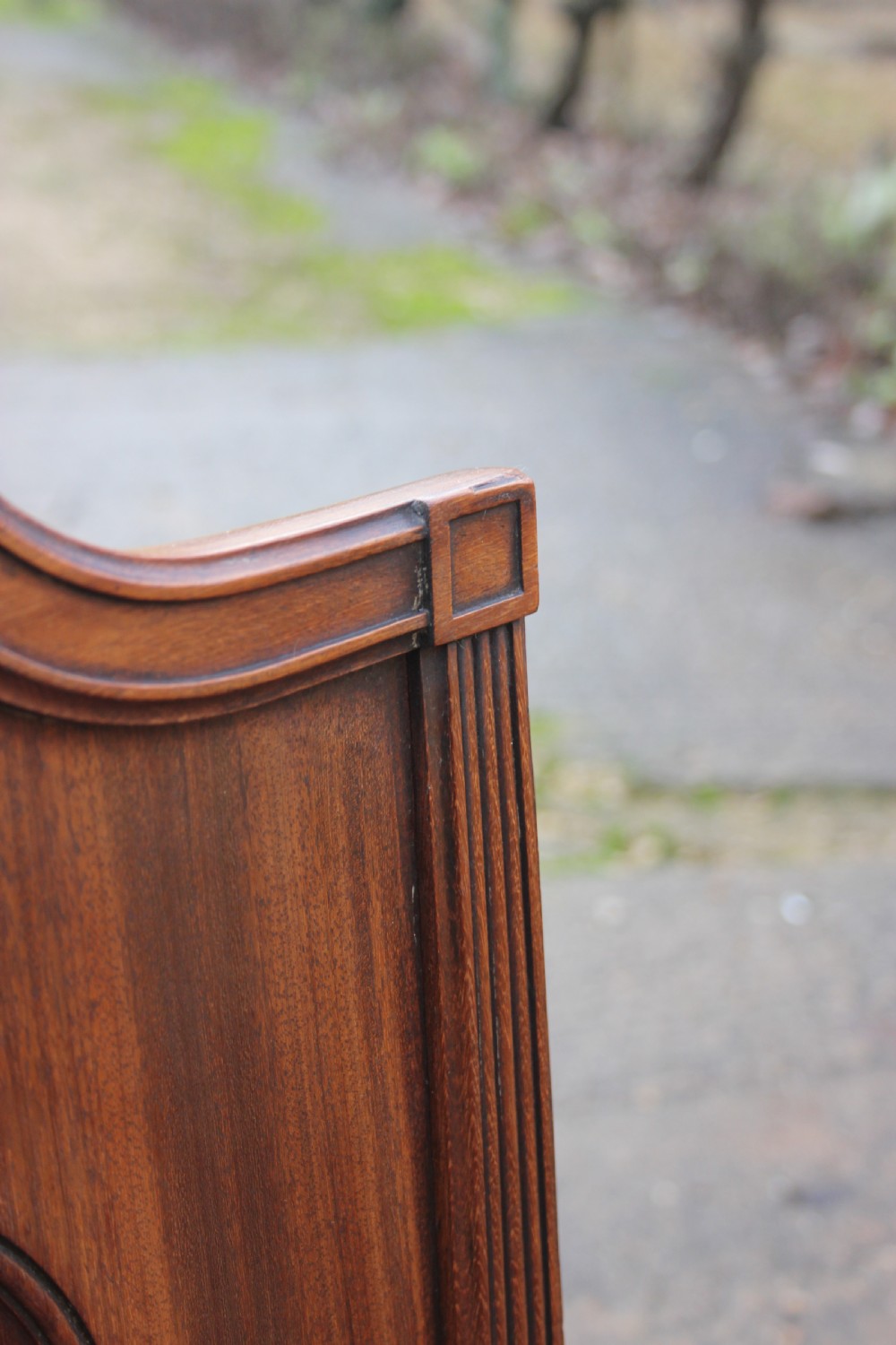 A pair of mahogany hall chairs featuring carved backrests with central circular mouldings, solid timber seats, and fluted turned front legs. View V
