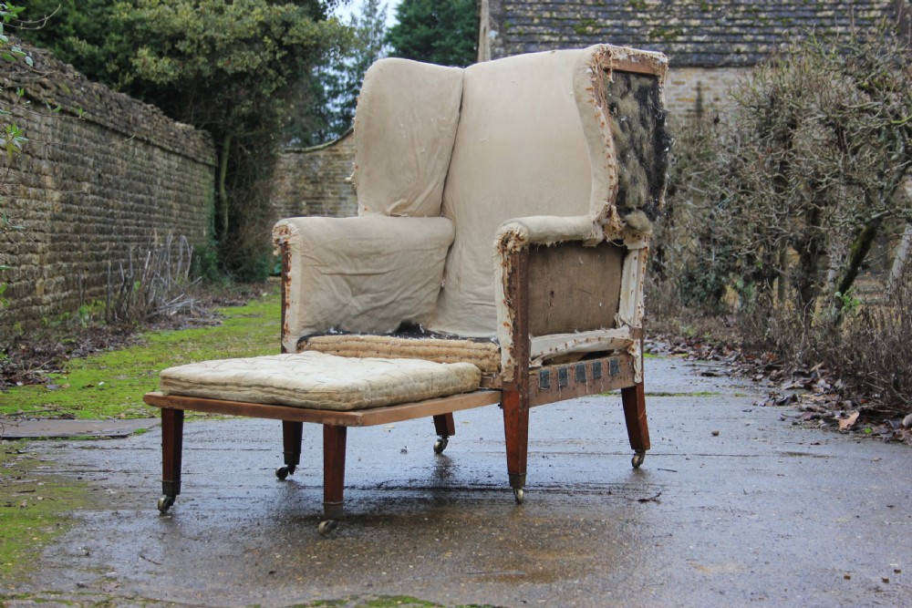 An early 19th century wingback armchair frame lined in neutral calico, featuring square tapered mahogany legs with brass castors. View III