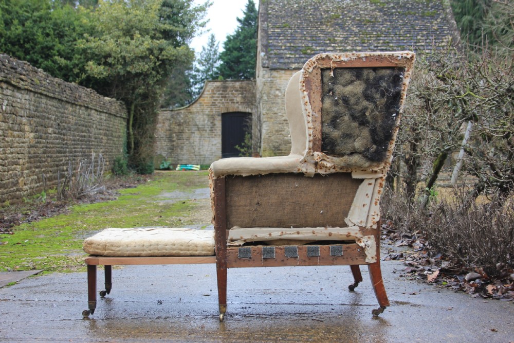 An early 19th century wingback armchair frame lined in neutral calico, featuring square tapered mahogany legs with brass castors. View IV