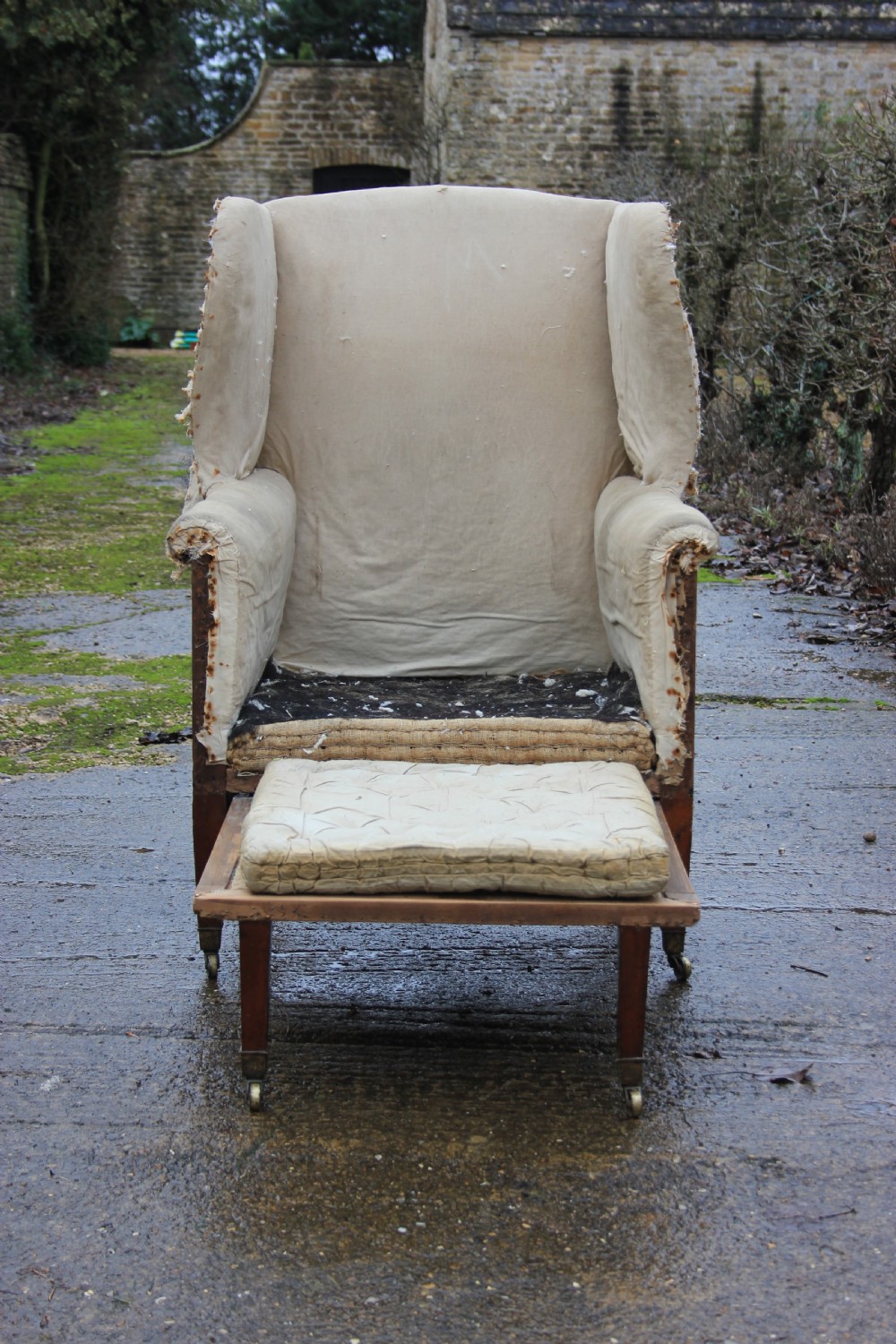 An early 19th century wingback armchair frame lined in neutral calico, featuring square tapered mahogany legs with brass castors. View VIII
