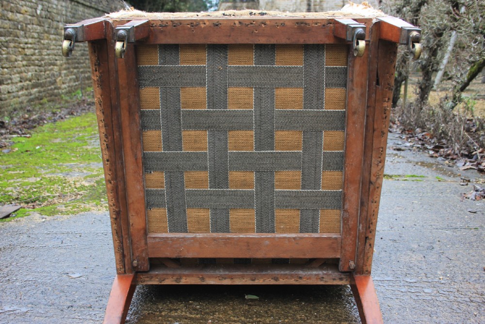 An early 19th century wingback armchair frame lined in neutral calico, featuring square tapered mahogany legs with brass castors. View IX