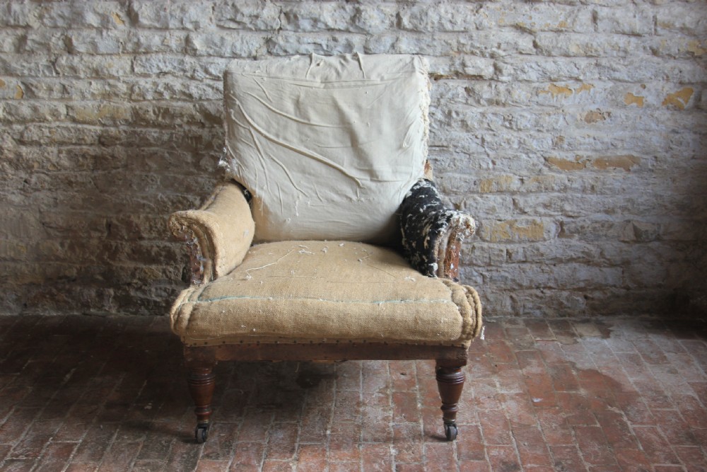 A Victorian deep-seated armchair frame with exposed calico and hessian sub-upholstery, featuring turned timber front legs on brass castors. View III