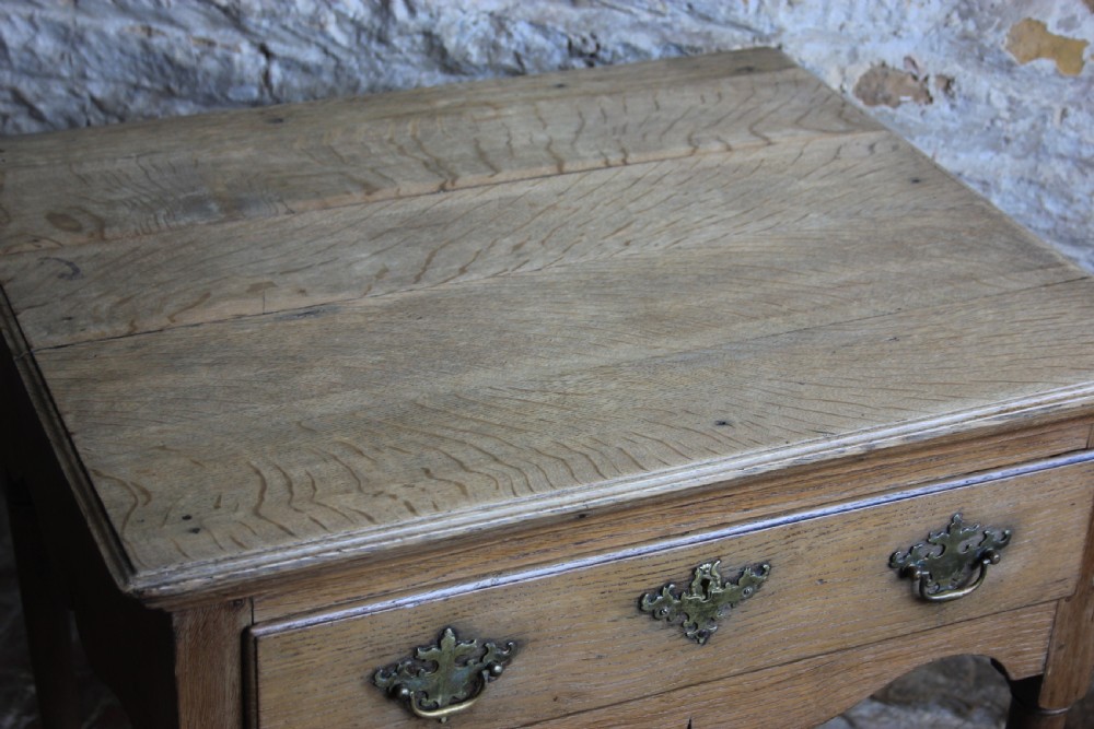 An 18th century pale oak lowboy featuring a single drawer with brass handles, a scalloped apron, and slender turned legs. View IV