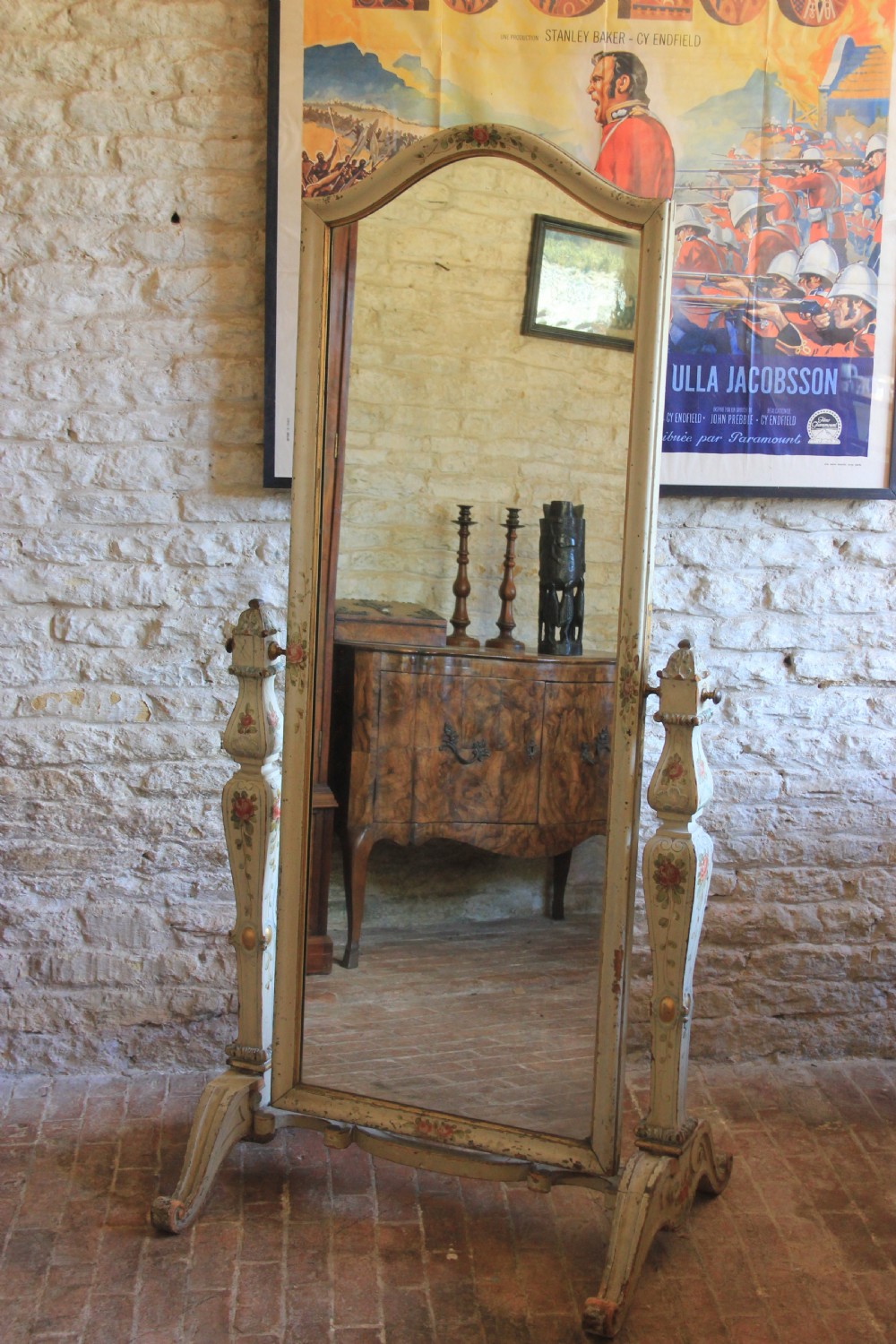 An antique 19th-century Italian cheval mirror featuring an off-white painted wooden frame decorated with hand-painted floral motifs and supported by carved trestle legs.
