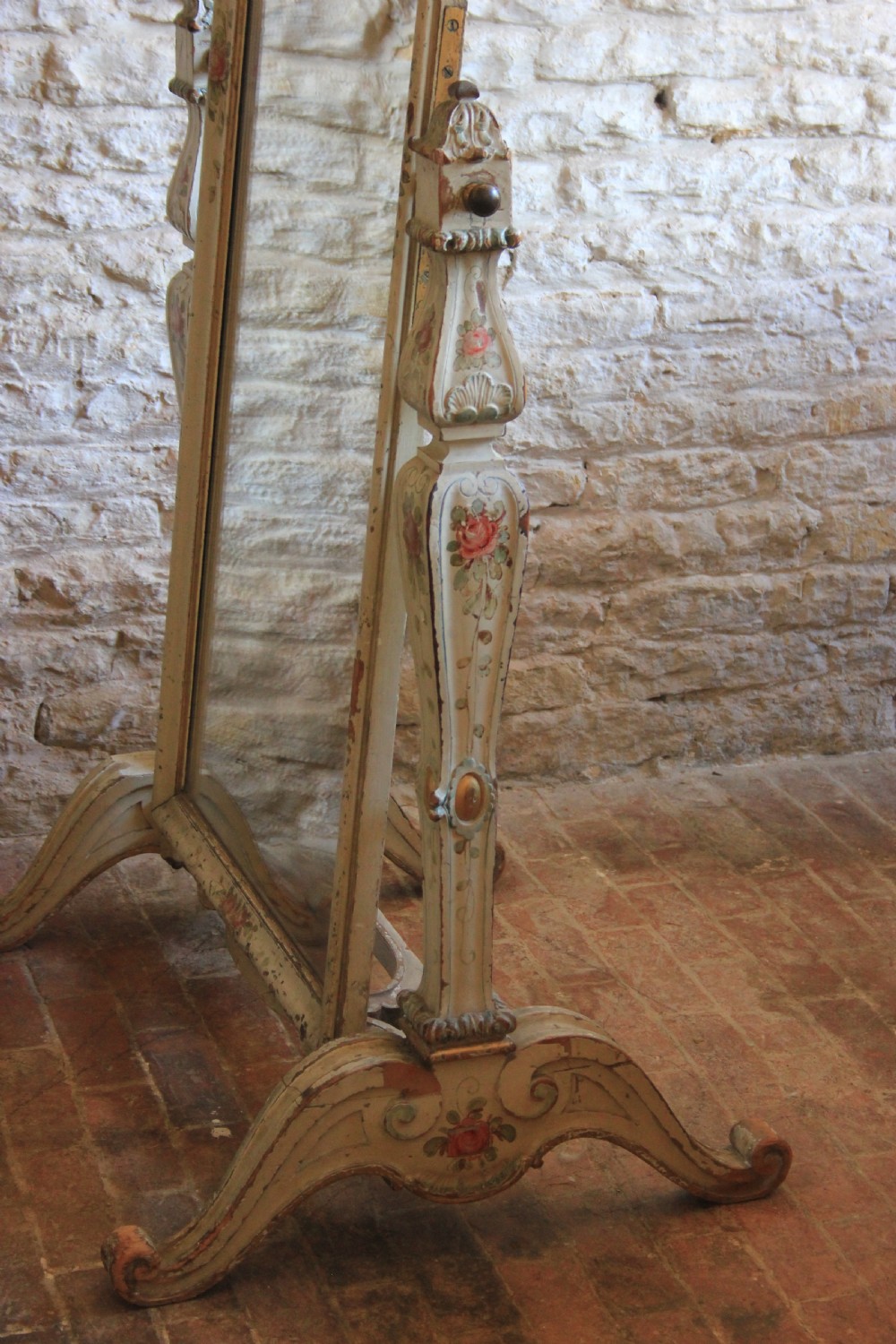 An antique 19th-century Italian cheval mirror featuring an off-white painted wooden frame decorated with hand-painted floral motifs and supported by carved trestle legs. View II