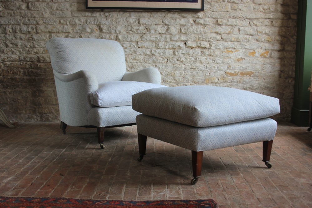 A light blue patterned upholstered Bridgewater armchair paired with a matching rectangular footstool, both raised on tapered mahogany legs with brass castors.