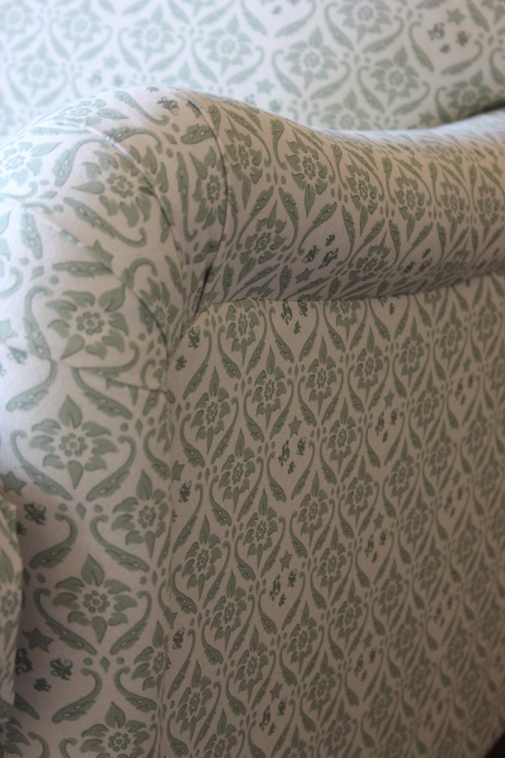 A two-seater Howard and Sons Ivor sofa upholstered in a light green and cream pattern with square tapered mahogany legs and brass castors. View IV