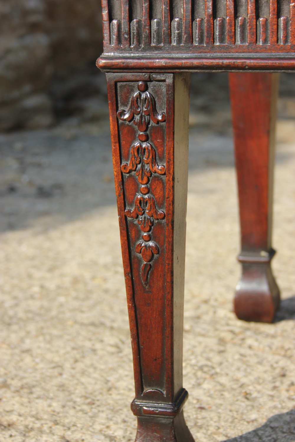 An 18th-century carved dark mahogany rectangular footstool frame featuring fluted aprons and carved legs, shown without upholstery. View II