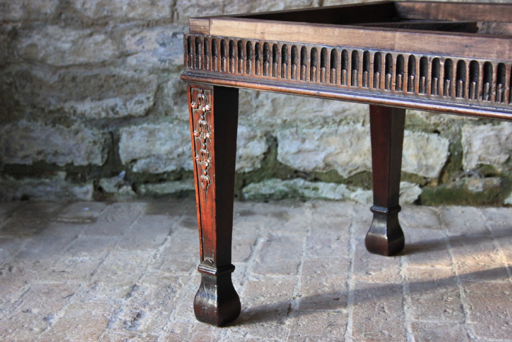 An 18th-century carved dark mahogany rectangular footstool frame featuring fluted aprons and carved legs, shown without upholstery. View III