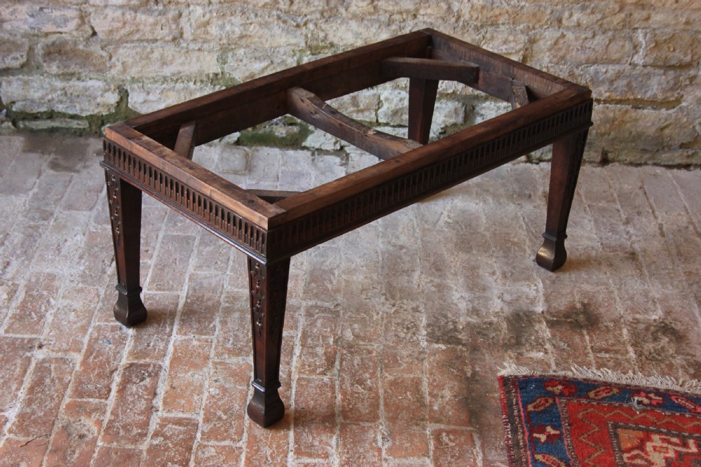 An 18th-century carved dark mahogany rectangular footstool frame featuring fluted aprons and carved legs, shown without upholstery. View IV