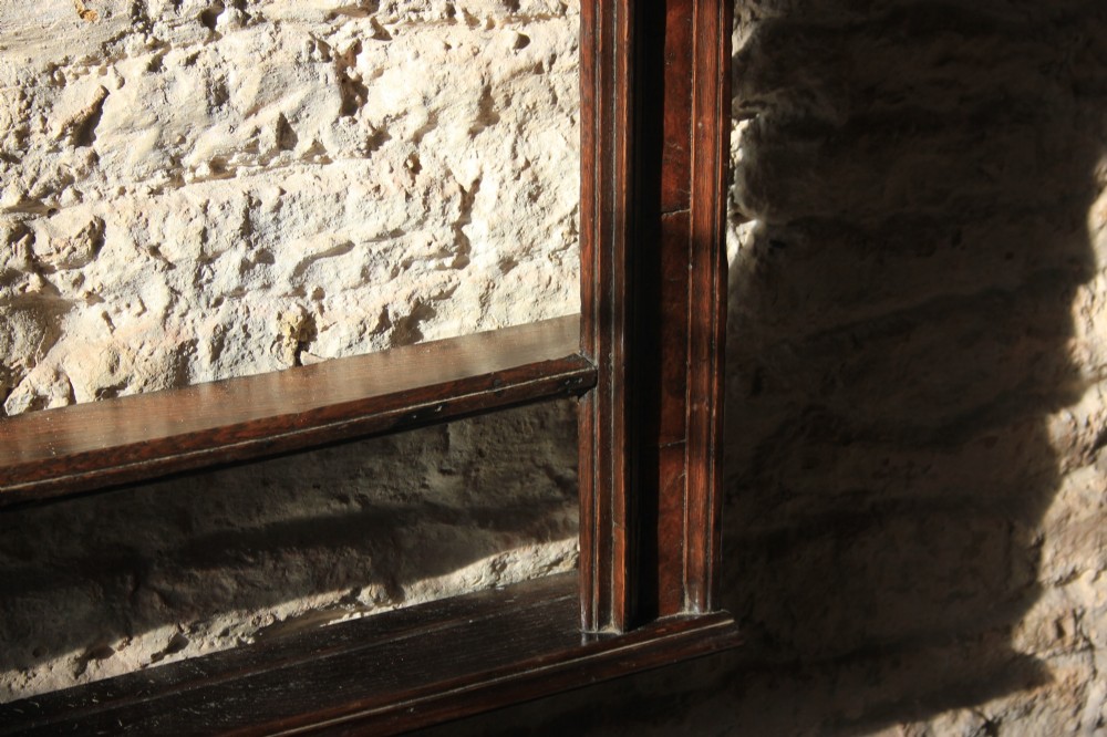 An 18th-century dark oak wall-mounted plate rack featuring a moulded cornice top and two horizontal shelf rails. View IV