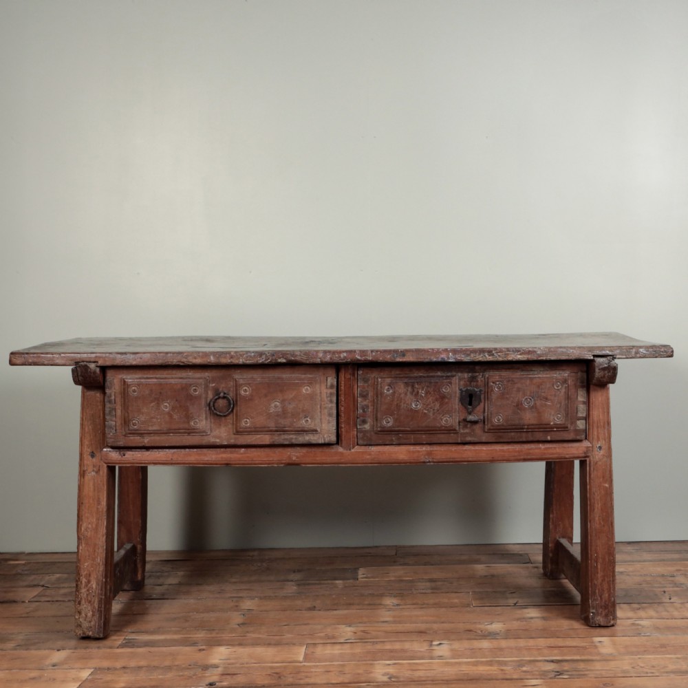 A 17th-century Spanish timber console table featuring two carved drawer fronts with iron ring handles.