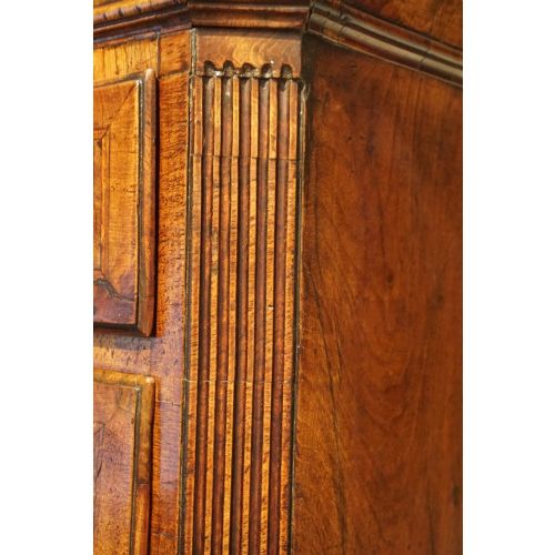 fig 4. A George II walnut tallboy featuring stacked drawers with decorative brass handles, bracket feet, and a sunburst motif on the bottom drawer.