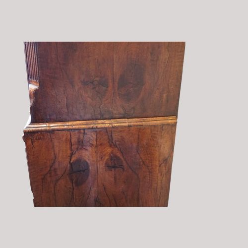 fig 6. A George II walnut tallboy featuring stacked drawers with decorative brass handles, bracket feet, and a sunburst motif on the bottom drawer.