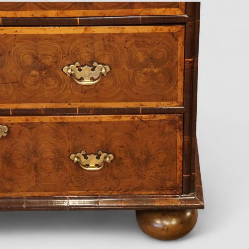 fig 1. A William and Mary period chest of drawers with oyster laburnum veneer, brass handles, and turned bun feet.