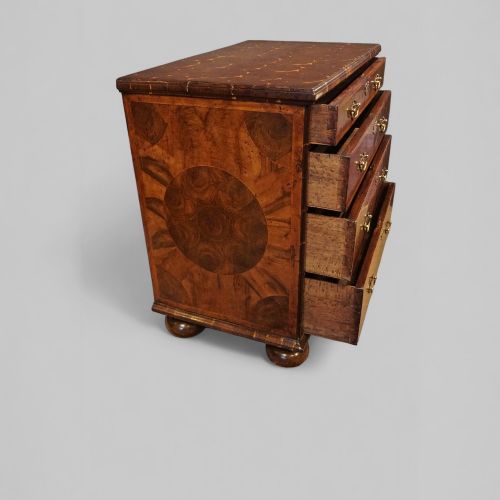 fig 3. A William and Mary period chest of drawers with oyster laburnum veneer, brass handles, and turned bun feet.
