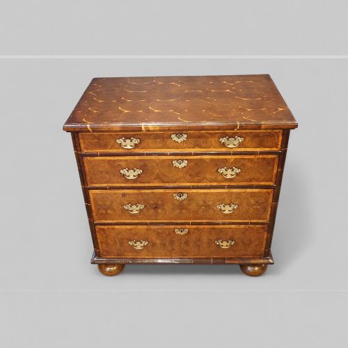 fig 5. A William and Mary period chest of drawers with oyster laburnum veneer, brass handles, and turned bun feet.