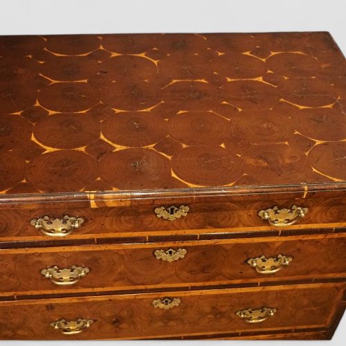 fig 8. A William and Mary period chest of drawers with oyster laburnum veneer, brass handles, and turned bun feet.