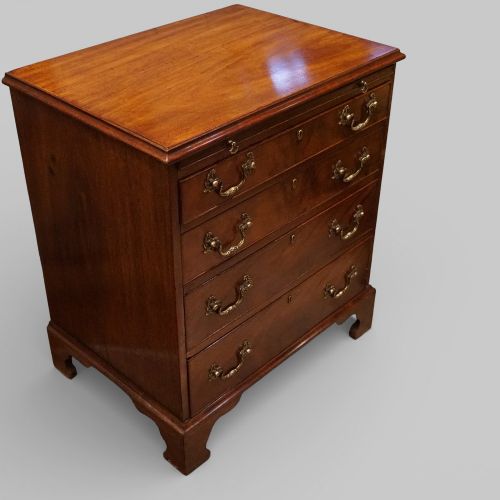 fig 1. A 19th-century small mahogany chest of drawers featuring four graduated drawers with brass swan-neck handles, a pull-out brushing slide, and bracket feet.