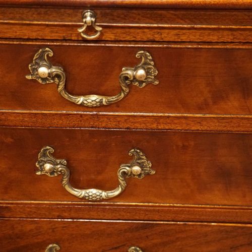 fig 3. A 19th-century small mahogany chest of drawers featuring four graduated drawers with brass swan-neck handles, a pull-out brushing slide, and bracket feet.